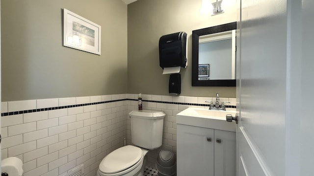 bathroom with a wainscoted wall, vanity, toilet, and tile walls