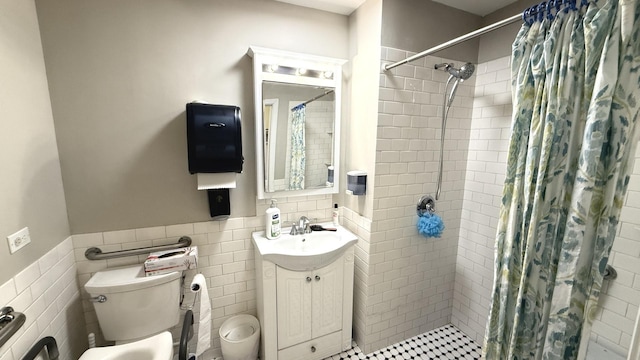 bathroom with wainscoting, tile walls, and tiled shower