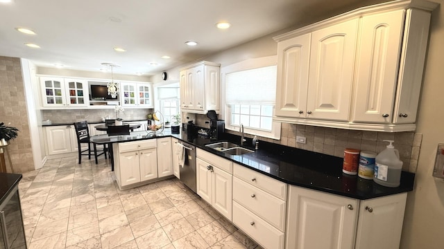 kitchen with dark countertops, a sink, and stainless steel dishwasher