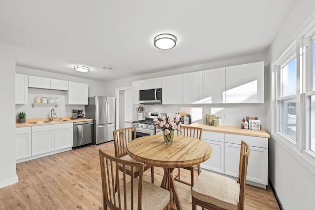 kitchen with stainless steel appliances, light countertops, a sink, and white cabinetry