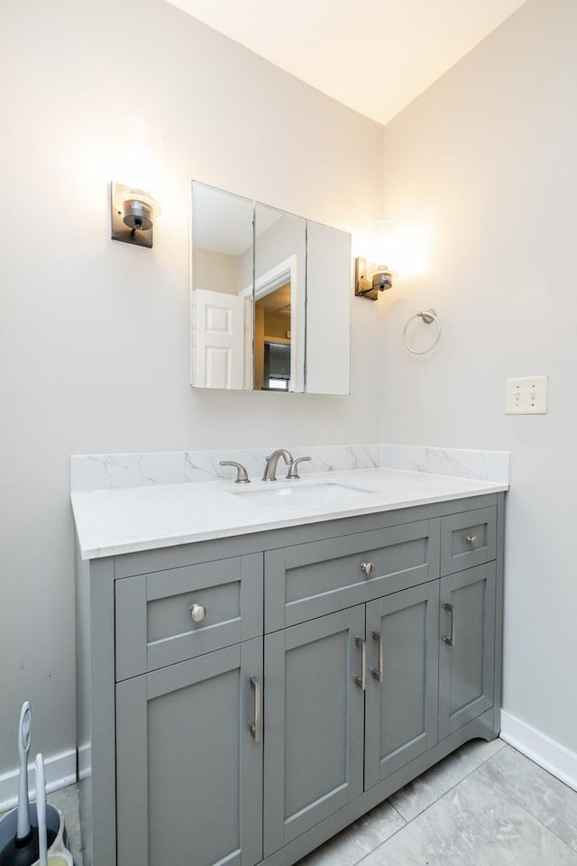 bathroom with marble finish floor, vanity, and baseboards