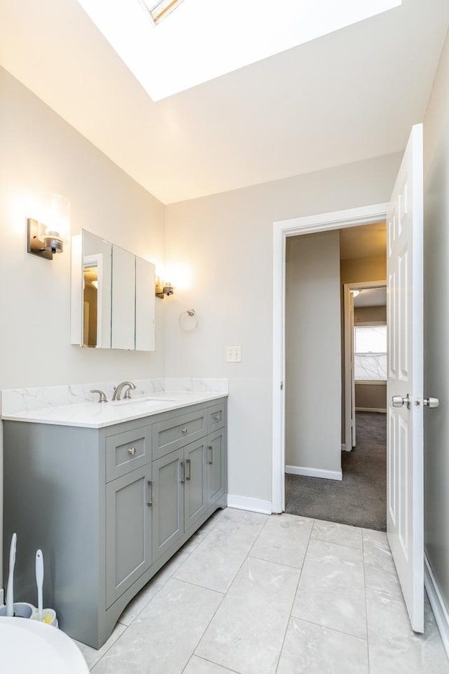 bathroom featuring a skylight, baseboards, and vanity