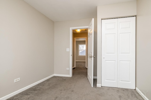 unfurnished bedroom featuring light carpet, baseboards, and a closet