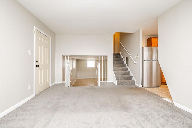 interior space featuring light carpet, baseboards, and stairs