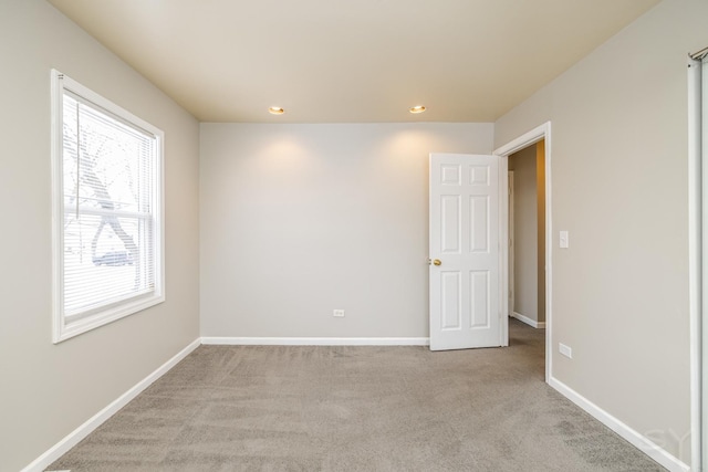 spare room featuring recessed lighting, light colored carpet, and baseboards