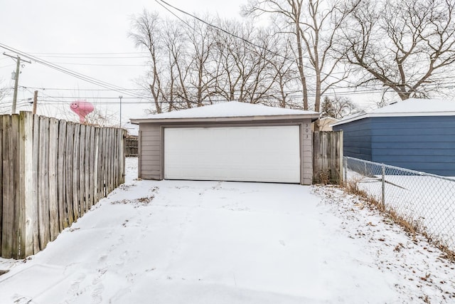 snow covered garage with a garage and fence