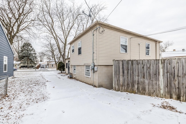 view of snow covered exterior with fence