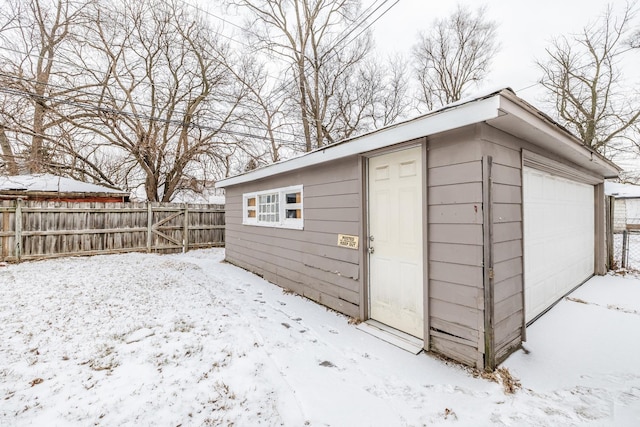 snow covered structure featuring fence and an outdoor structure