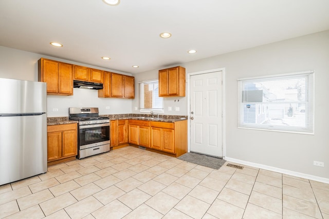 kitchen with stainless steel appliances, brown cabinetry, recessed lighting, and under cabinet range hood