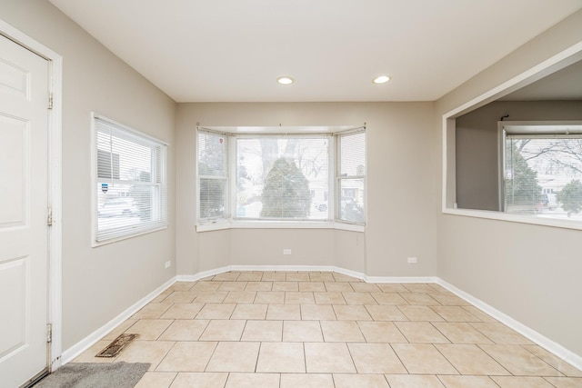 unfurnished room with a wealth of natural light, visible vents, and baseboards