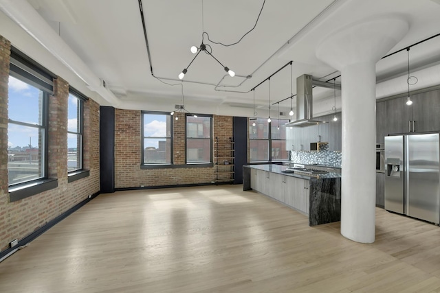 kitchen with stainless steel appliances, brick wall, open floor plan, modern cabinets, and island exhaust hood