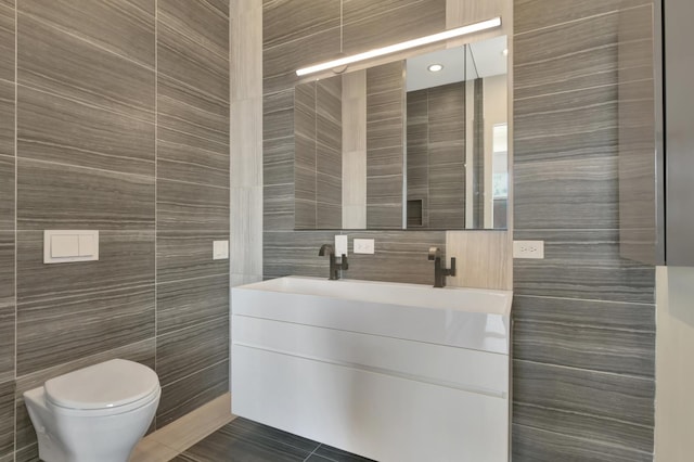 bathroom with toilet, tile walls, and vanity