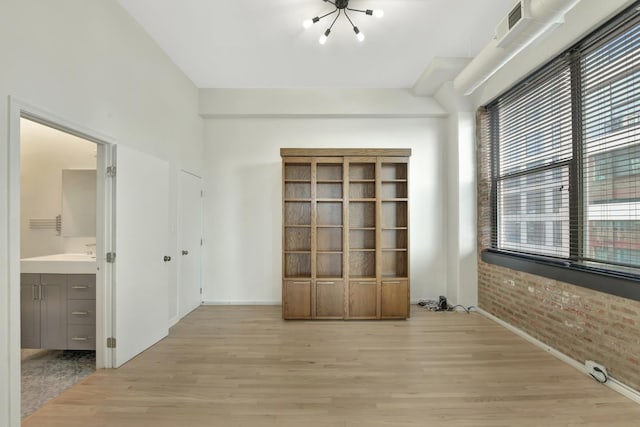 interior space with light wood-style floors, visible vents, and brick wall