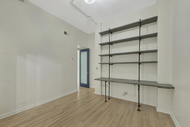 spare room featuring light wood finished floors, visible vents, and baseboards