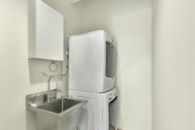 clothes washing area with stacked washer / drying machine, laundry area, and a sink