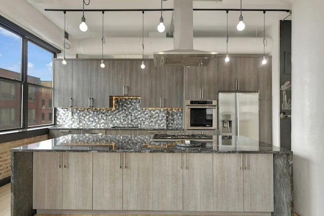 kitchen with appliances with stainless steel finishes, dark stone counters, pendant lighting, and modern cabinets