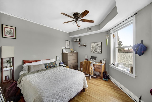 bedroom with light wood finished floors, baseboards, visible vents, and ceiling fan