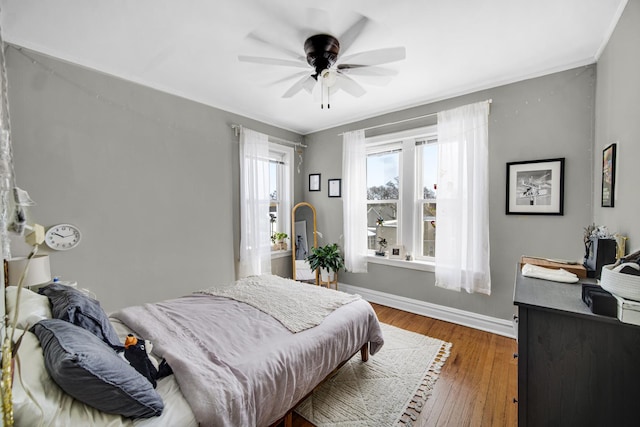 bedroom with ceiling fan, wood finished floors, and baseboards