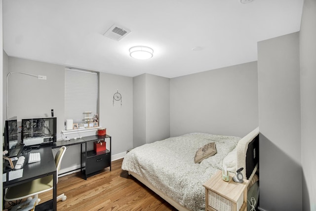 bedroom featuring visible vents, light wood-style flooring, and baseboards