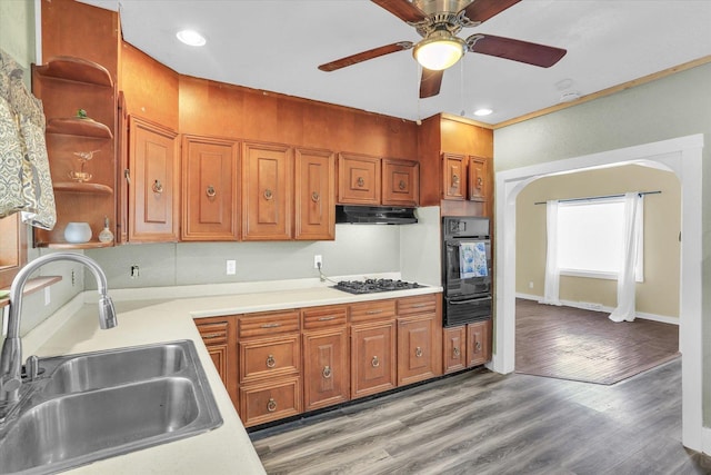 kitchen featuring under cabinet range hood, a sink, gas stovetop, black oven, and open shelves