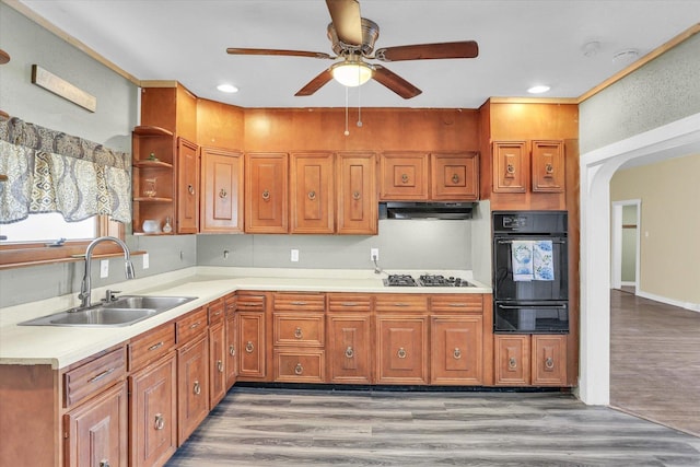 kitchen with arched walkways, a sink, gas cooktop, a warming drawer, and black oven