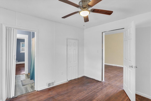 unfurnished bedroom featuring dark wood-style floors, baseboards, visible vents, and a ceiling fan