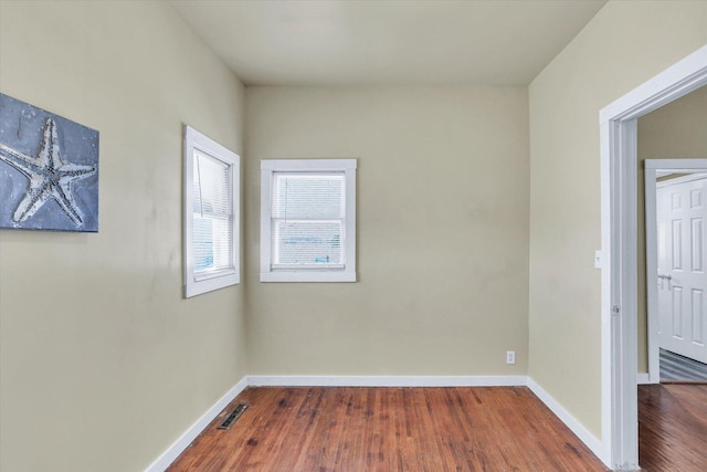 empty room featuring visible vents, baseboards, and wood finished floors