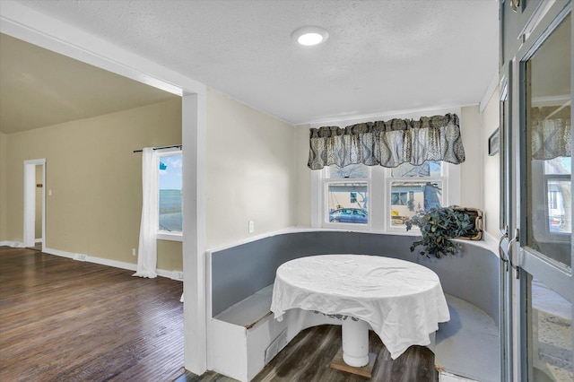 dining room featuring a textured ceiling, wood finished floors, and baseboards