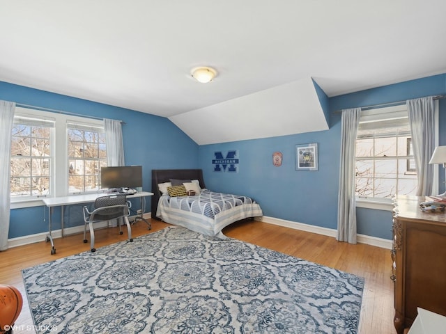 bedroom featuring baseboards, multiple windows, wood finished floors, and vaulted ceiling