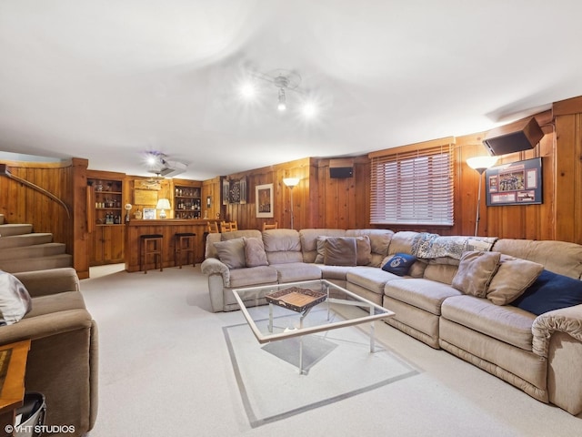 carpeted living area with wood walls and a bar