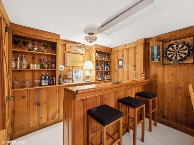 bar featuring light carpet, a dry bar, and wood walls