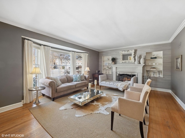 living room featuring baseboards, a lit fireplace, wood-type flooring, and ornamental molding