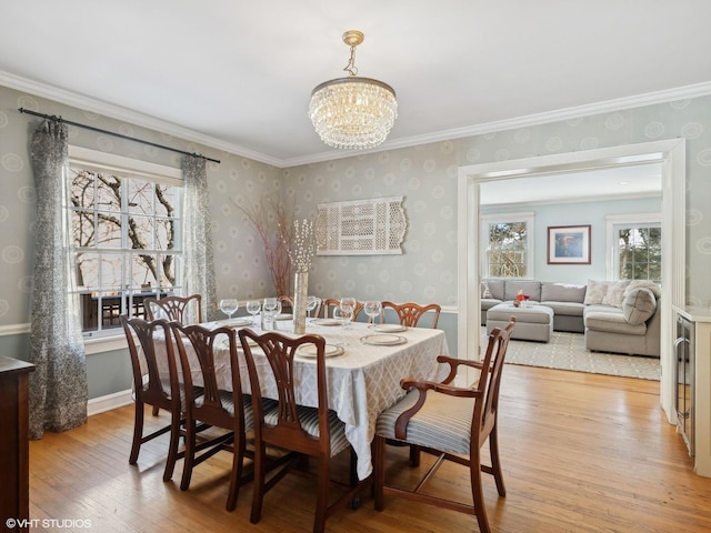 dining room featuring baseboards, light wood finished floors, wallpapered walls, ornamental molding, and a notable chandelier