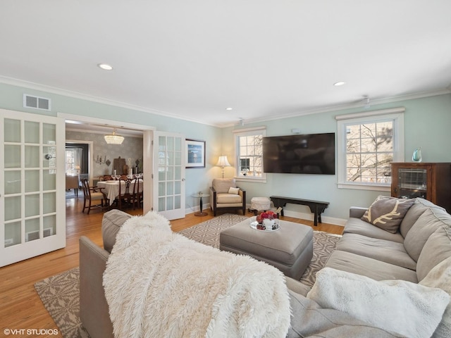 living area with visible vents, ornamental molding, french doors, and wood finished floors