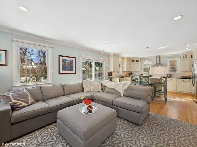 living area featuring light wood-style flooring, recessed lighting, and ornamental molding