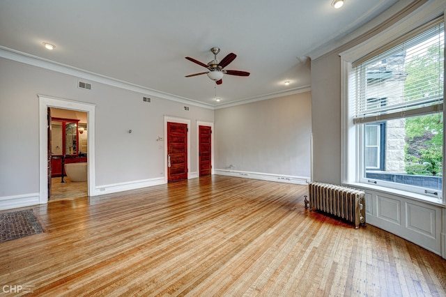 empty room featuring visible vents, baseboards, radiator, ornamental molding, and light wood-type flooring