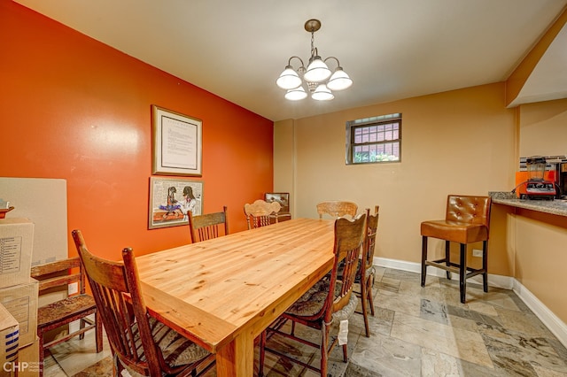 dining area with stone tile floors, baseboards, and a notable chandelier