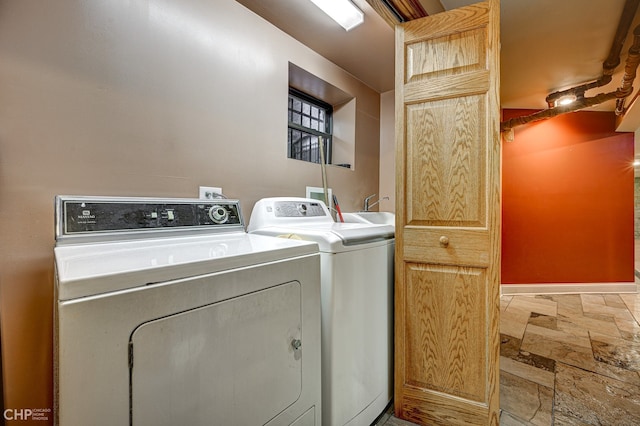 laundry room with laundry area, washing machine and dryer, stone finish floor, and baseboards