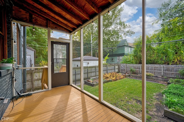 unfurnished sunroom featuring lofted ceiling, plenty of natural light, and wood ceiling