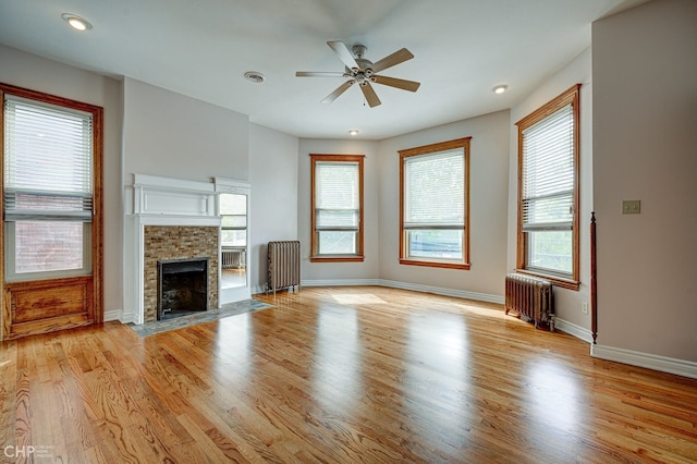 unfurnished living room featuring radiator, a fireplace with flush hearth, visible vents, and light wood-style flooring