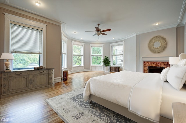 bedroom featuring radiator, a fireplace, crown molding, and multiple windows