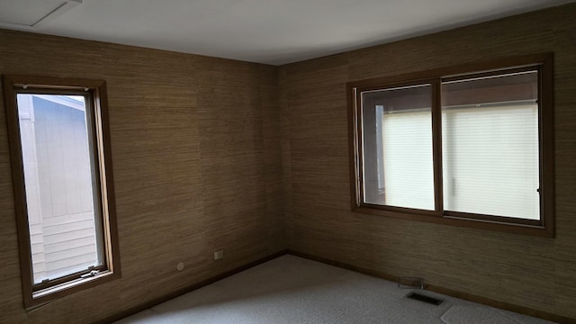 unfurnished room with visible vents, plenty of natural light, and carpet flooring