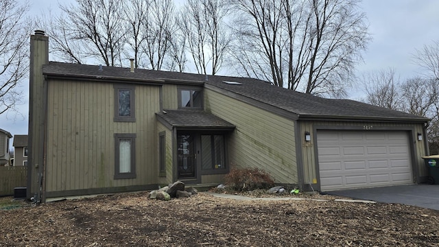 view of front of property featuring a garage, central AC, a shingled roof, driveway, and a chimney