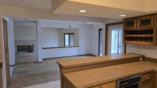 kitchen with recessed lighting, a tiled fireplace, glass insert cabinets, dishwasher, and baseboards