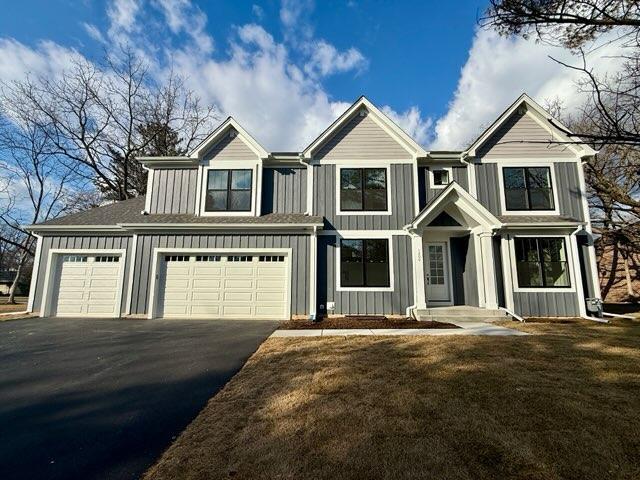 view of front of home featuring driveway, a garage, a front lawn, and board and batten siding