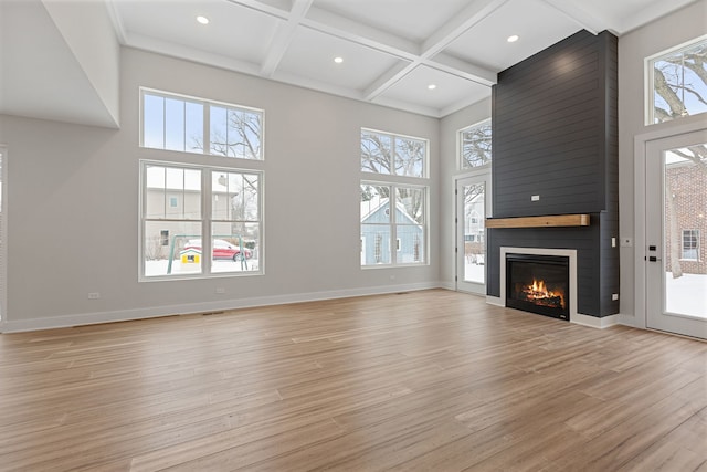 unfurnished living room featuring light wood-style floors, coffered ceiling, baseboards, and a high ceiling