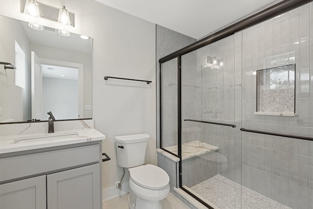 full bathroom featuring baseboards, a shower stall, toilet, and vanity