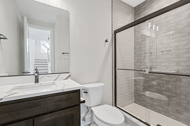 bathroom with toilet, a shower stall, and vanity