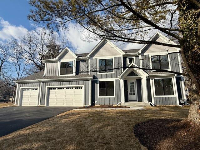 view of front of home featuring board and batten siding, a garage, and aphalt driveway