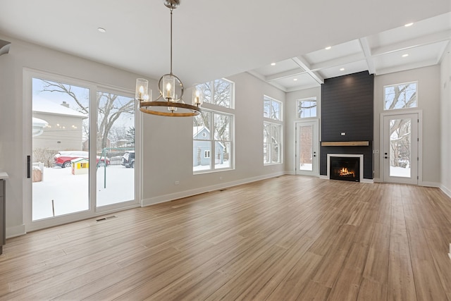 unfurnished living room featuring light wood-style floors, a fireplace, coffered ceiling, and beam ceiling